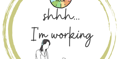 A golden circle - in it the Power Hour logo. underneath text in cursive shhhhh...I'm working. And underneath that a comic of a person sitting on the floor working on a laptop wearing headphones.