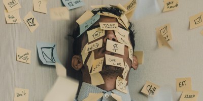 Young man covered in sticky notes, work overload